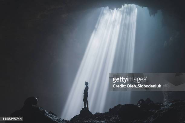 man standing in jomblan cave in sunbeams - cave stock pictures, royalty-free photos & images