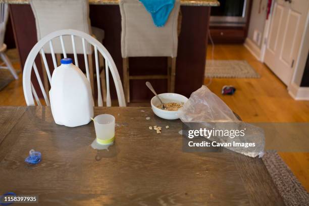 messy kitchen table, milk jug, spilled milk, cereal and pacifier - spilt milk stock pictures, royalty-free photos & images