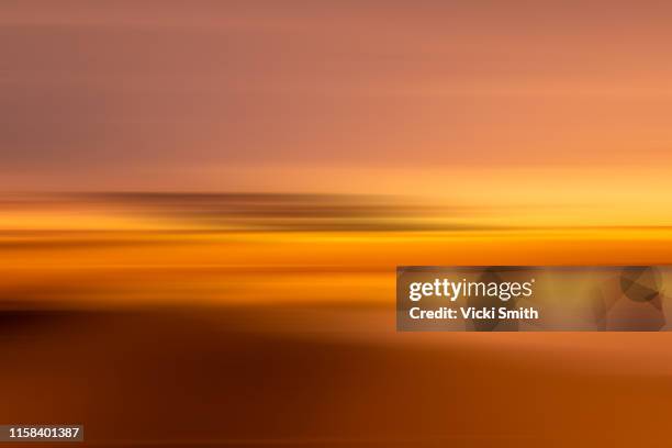 motion effect of a vibrant colored sunrise over the ocean - fokus auf den hintergrund stock-fotos und bilder
