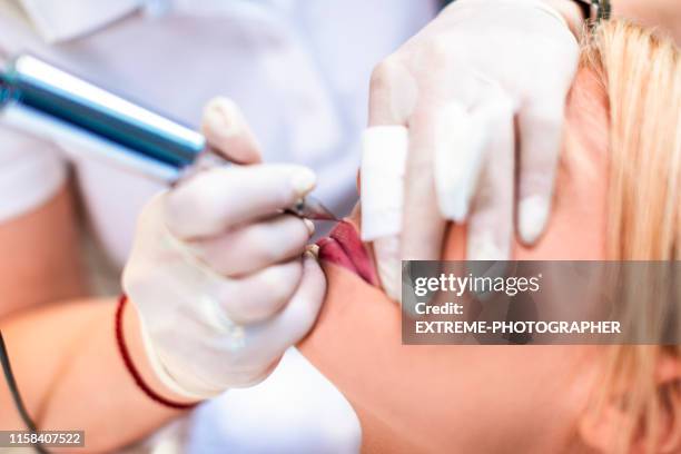 esthéticienne appliquant le rouge à lèvres permanent de maquillage à une jeune femme dans un centre cosmétique - maquillage permanent photos et images de collection