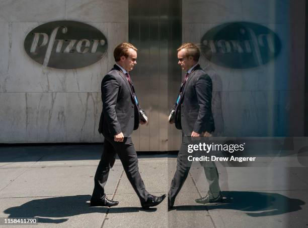 Man is reflected in a bus stop window as he walks past Pfizer world headquarters in Midtown Manhattan on July 29, 2019 in New York City. On Monday...