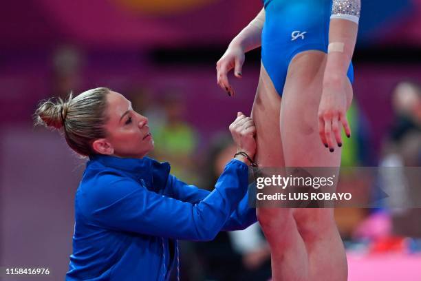 Coach Maggie Haney rub US Riley McCusker's legs before she competes in Floor during the Women's Individual All-Around Final event of the Lima 2019...