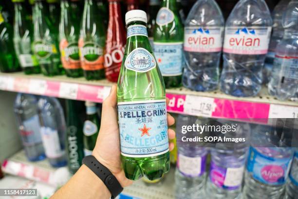 Customer holds a bottle of SanPellegrino sparkling natural mineral water in a Carrefour supermarket in Shanghai.