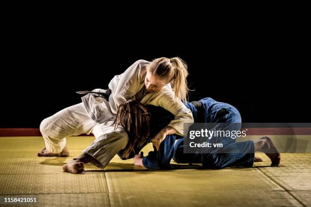 deux judokas féminins luttant sur un tapis de tatami - jiu jitsu photos et images de collection