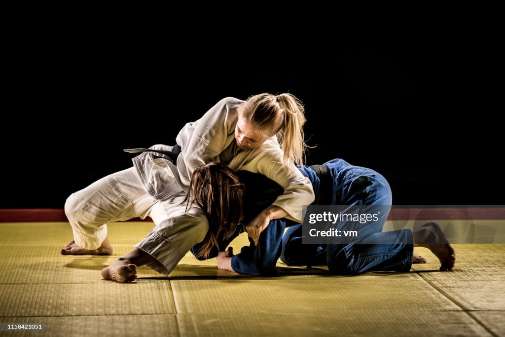 Due judoka femminili che lottano su un tappetino tatami
