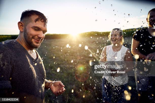 playful friends splashing with water from disposable cups in the countryside - erwachsener über 30 stock-fotos und bilder