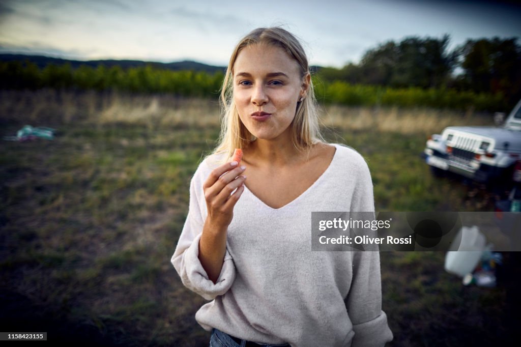 Portrait of young woman eating a carrot in the countryside