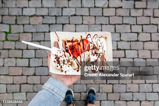 Eating Belgian waffle with sweet toppings and fresh fruits at the town square, personal perspective view Eating Belgian waffle with sweet toppings and fresh fruits at the town square, personal perspective view