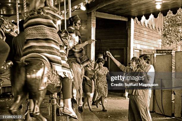 Woman offering popcorn to a man riding the carousel, dressed in a serape and a hat, who is pointing at her at the 1st Elysian Park Love-In on March...