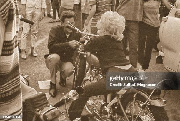 Woman in a bleached, boufant hair-do, sitting on a motorcycle, seen from behind at the 1st Elysian Park Love-In on March 26, 1967 in Los Angeles,...