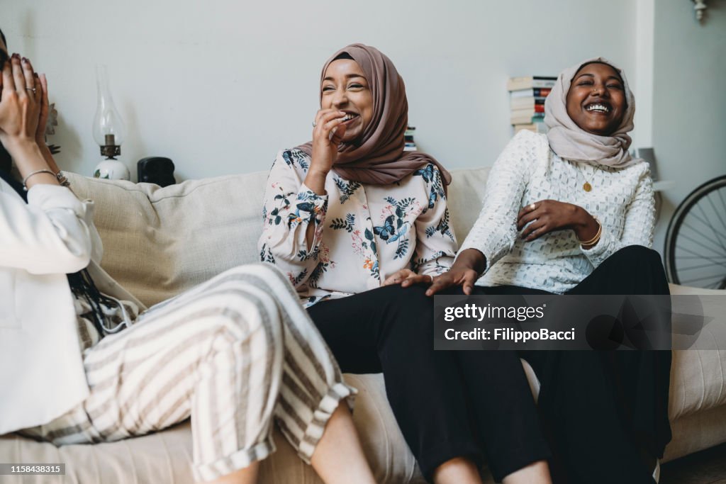 Drei Freunde im Gespräch sitzend auf dem Sofa zu Hause