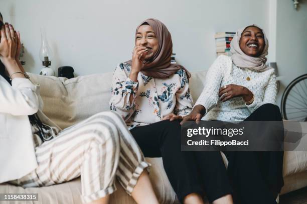 three friends talking together sitting on the sofa at home - islamismo imagens e fotografias de stock