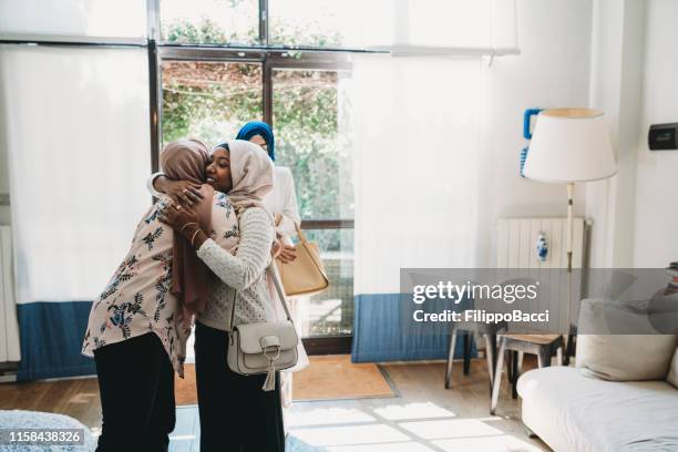 young woman welcoming her friends at home - egyptian family stock pictures, royalty-free photos & images