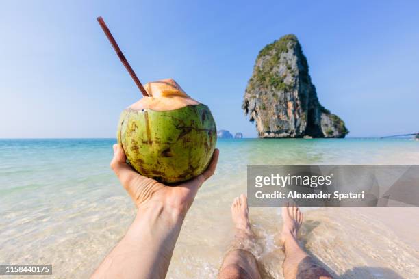 enjoying beach view and drinking coconut water, personal perspective view - thailand strand stock-fotos und bilder