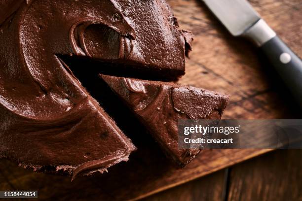 torta al cioccolato indulgente affettata contro una superficie rustica invecchiata in legno. - chocolate cake foto e immagini stock