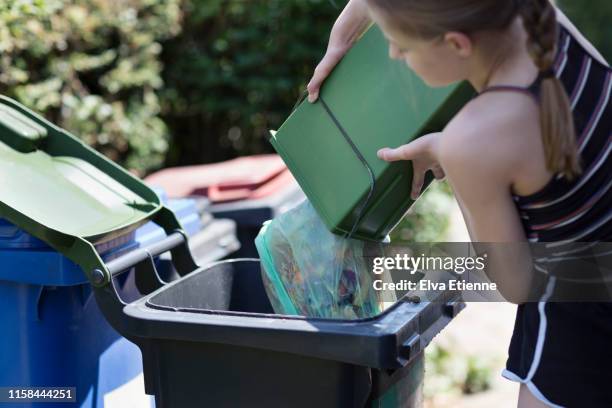 girl emptying food scraps inside a biodegradable bag directly into a food recycling bin - unloading stock pictures, royalty-free photos & images