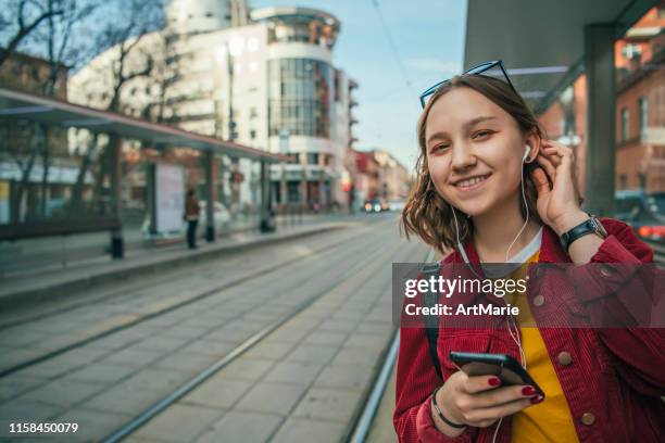 teenager-mädchen wartet auf straßenbahn, bus oder taxi - straßenbahnstrecke stock-fotos und bilder