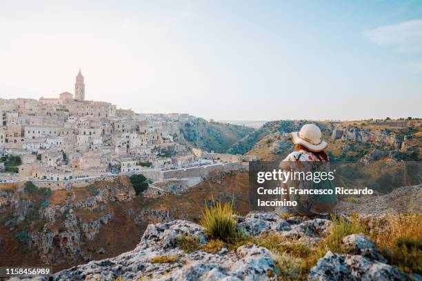 woman tourist admiring the view of matera at sunset. murgia belvedere, basilicata, italy - southern rock stock pictures, royalty-free photos & images