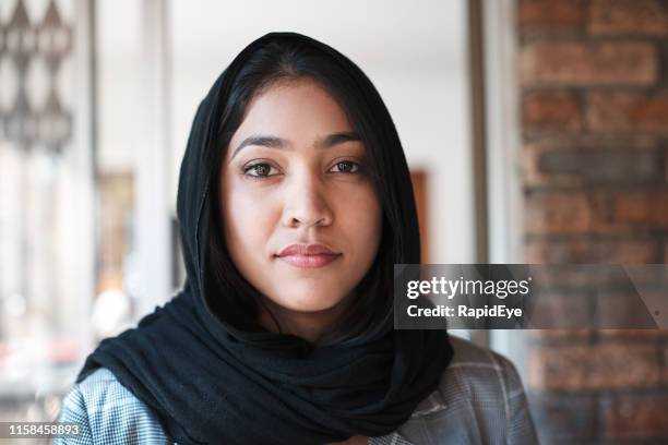 joven musulmana en hiyab se encuentra en la puerta de su casa - islamismo fotografías e imágenes de stock