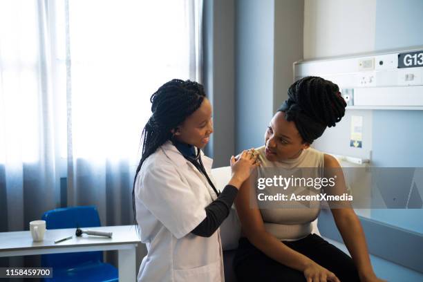 young doctor talking with patient in hospital ward - doctors in africa stock pictures, royalty-free photos & images