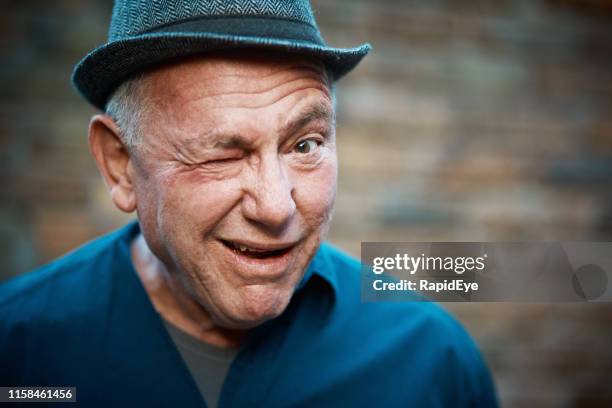 senior mann zwinkert ungeschickt - zwinkern stock-fotos und bilder