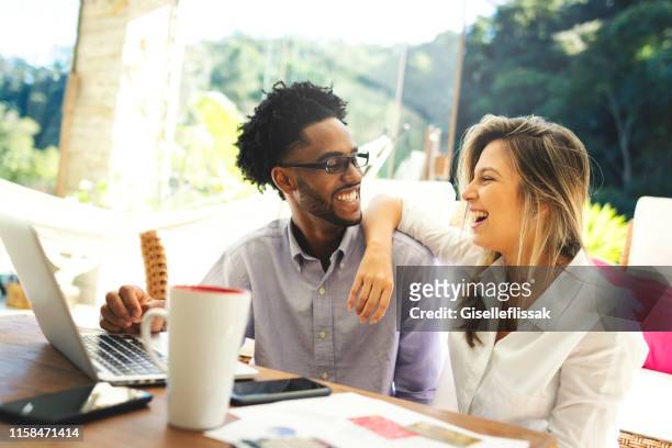 couple using laptop, credit card and cell phone, sitting in the living room - financial wellbeing stock pictures, royalty-free photos & images