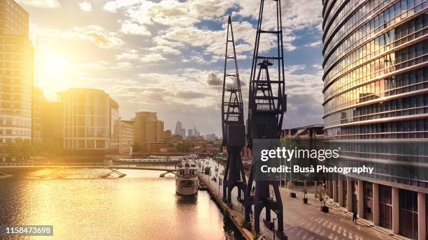 historic port gantry cranes in the docklands at canary wharf, east london, united kingdom - sunset on canary wharf stock-fotos und bilder