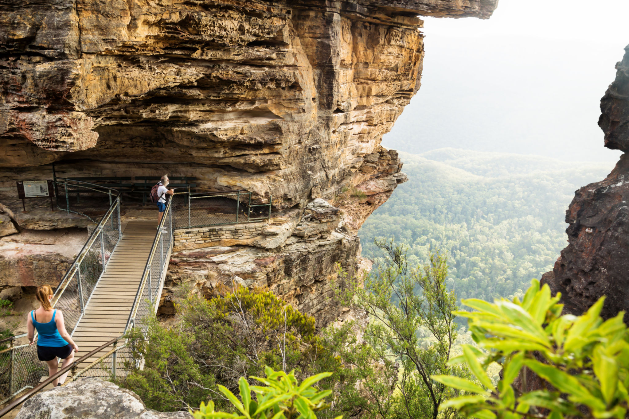 Bridge to rock formation Three Sisters with hikers looking into the valley, Katoomba, New South Wales, Australia Bridge to rock formation Three Sisters with hikers looking into the valley, Katoomba, New South Wales, Australia