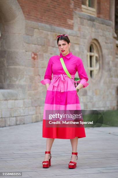 Guest is seen on the street attending 080 Barcelona Fashion Week wearing pink shirt, pink/red stripe skirt, pink sunglasses, neon green/pink...