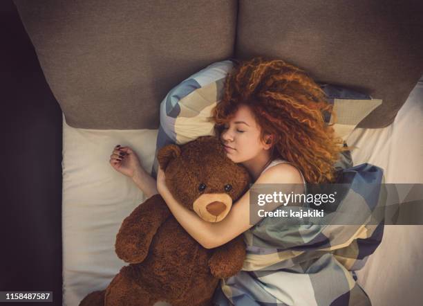 retrato de una hermosa joven con oso de peluche durmiendo en la cama en casa - soft toy fotografías e imágenes de stock