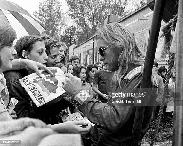 Gregg Allman of the Allman Brothers Band signs autographs on arriving at an in-store appearance at Peaches Records on October 5, 1975 in Atlanta,...