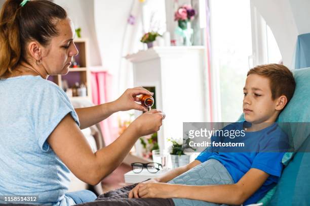 mother giving her son syrup - caucasian woman sick in bed coughing stock pictures, royalty-free photos & images