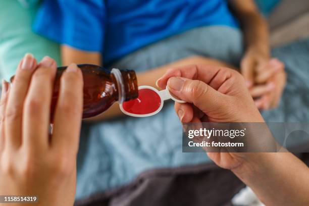 woman's hand pouring syrup for sick child - syrup stock pictures, royalty-free photos & images