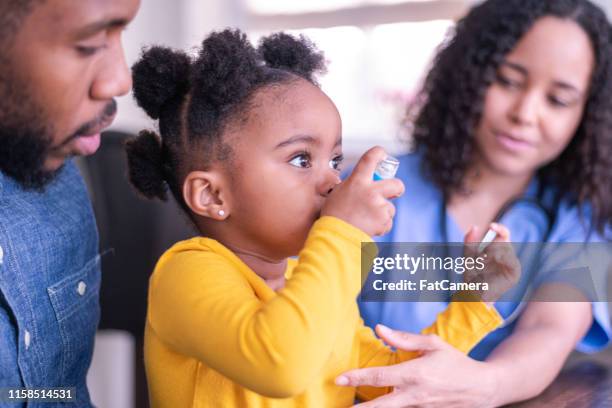 girl at doctor's appointment using an asthma inhaler - family pediatrician stock pictures, royalty-free photos & images