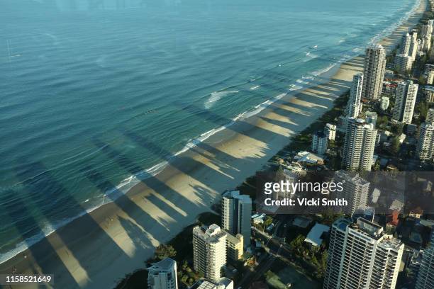 tall buildings along the ocean front casting their shadow out onto the sand and ocean - gold coast skyline stock-fotos und bilder