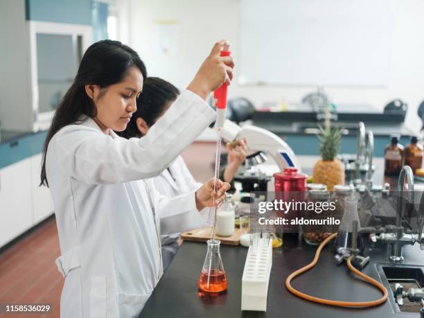 lab student standing and filling flask with liquid - scientific flask stock pictures, royalty-free photos & images