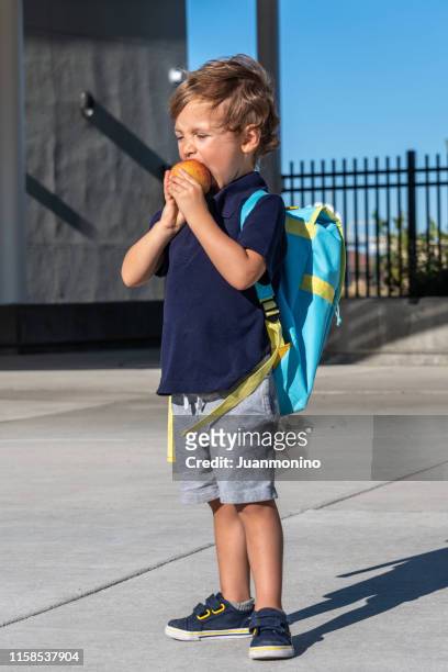 retour à l'école, petit enfant de garçon ayant une pomme dans son premier jour d'école - child eat side photos et images de collection