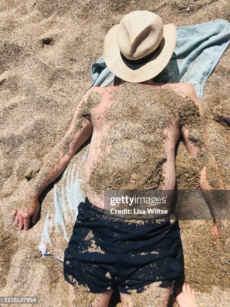 overhead view of a man covered in sand on the beach - bury fotografías e imágenes de stock
