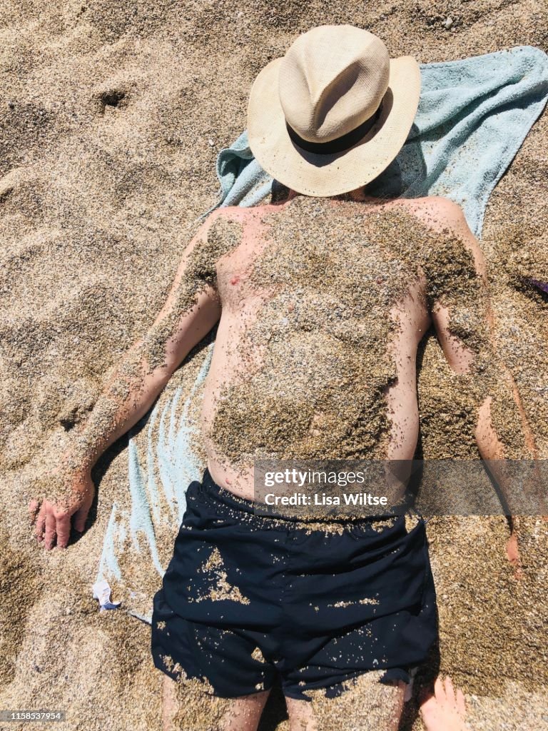 Overhead view of a man covered in sand on the beach