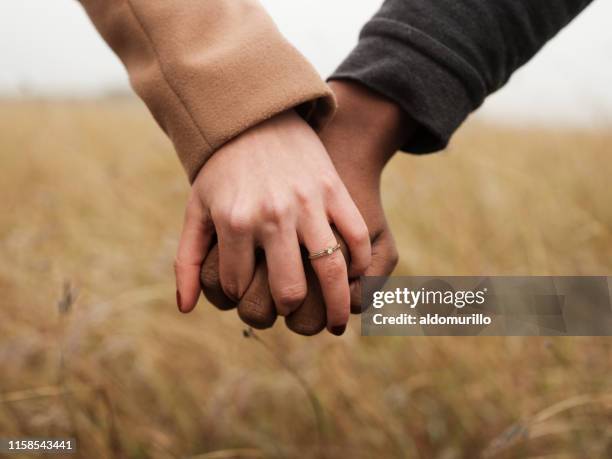 pareja comprometida cogidos de la mano - anillo de compromiso fotografías e imágenes de stock