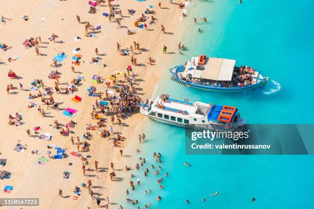 vista dell'affollata spiaggia di navagio a zante - imbarcazione per passeggeri foto e immagini stock