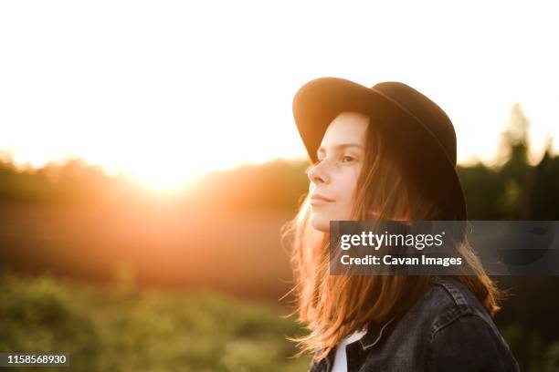 portrait of a beautiful young woman  standing against clear sky - golden hour woman stock pictures, royalty-free photos & images