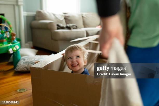 happy toddler boy looks up at brother smiling inside cardboard toy - kids fort stock pictures, royalty-free photos & images