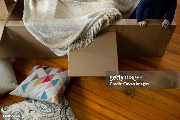 child plays indoors in airplane made of cardboard covered with blanket - kids fort imagens e fotografias de stock