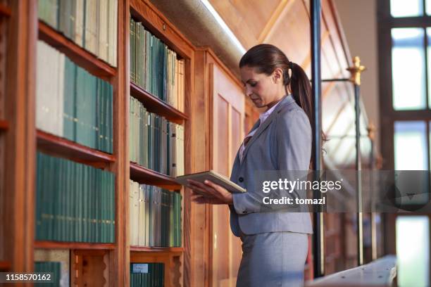 giovane donna che legge un libro in biblioteca pubblica - studio legale foto e immagini stock