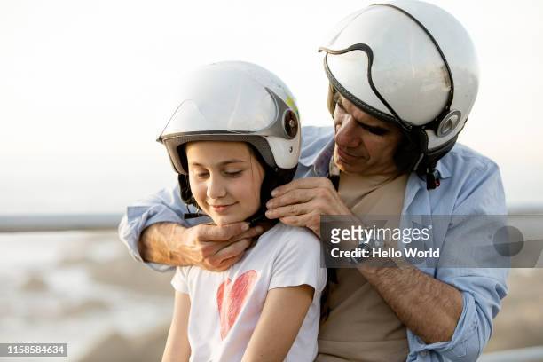 Father fastens daughter's motorcycle helmet