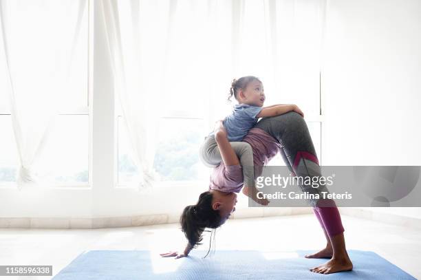 woman doing yoga with daughter on her back - baby carrier outside bildbanksfoton och bilder