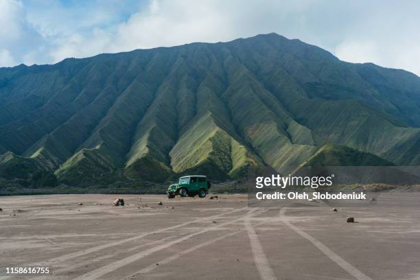 schilderachtig uitzicht op ouderwetse suv rijden door de woestijn in de buurt van bromo vulkaan - internationaal monument stockfoto's en -beelden