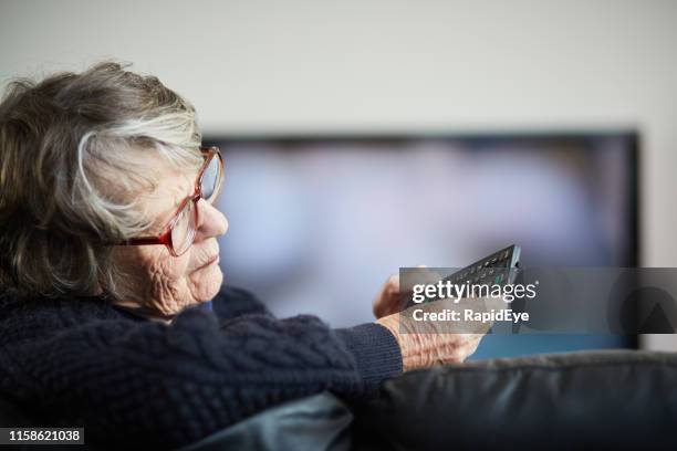 senior vrouw geïrriteerd door haar tv-afstandsbediening - faze rug stockfoto's en -beelden