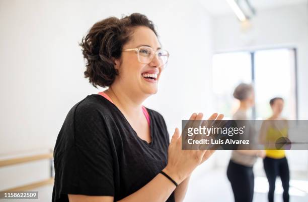 cheerful woman clapping hands at fitness studio - large group of people photos et images de collection
